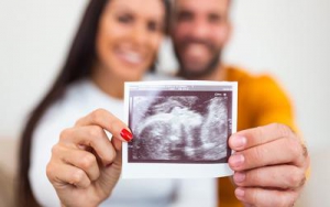 Photo of couple holding ultrasound photo of baby
